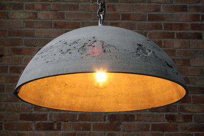 Our moon inspired Lunar gfrc concrete pendant light with its half sphere concrete lampshade approximately 520mm in diameter and a height of around 200mm. Showing the chain, hook and the lampshade surface detail and inside with the bulb lit