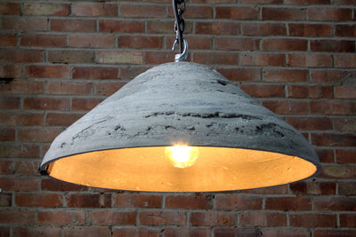 Our Gleam artisan concrete pendant light showing chain hook and concrete surface detail, and inner area of the shade with the bulb lit